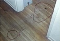 Bloody footprints of Jeffrey MacDonald in the hallway, exiting the bedroom of Kristen MacDonald.<BR><BR>CID Exhibit D217 (floorboards marked F through K, circled at left) was made by MacDonald's left foot.  The print was made in human blood, but typing was precluded due to the paucity or contamination of the stain.<BR><BR>CID Exhibit D215, circled at right, was the left footprint of Jeffrey MacDonald in Type A blood (the blood type of Colette MacDonald).  CID Exhibit D216, made by MacDonald's right foot, was located between the two circled areas.